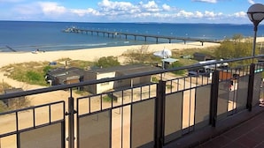 A beach view with a pier extending into the water, a sandy beach, and a few buildings in the background. - Panorama Hotel Bansin (Heringsdorf)