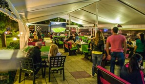 Un área de comedor al aire libre con mesas y sillas bajo una carpa.
