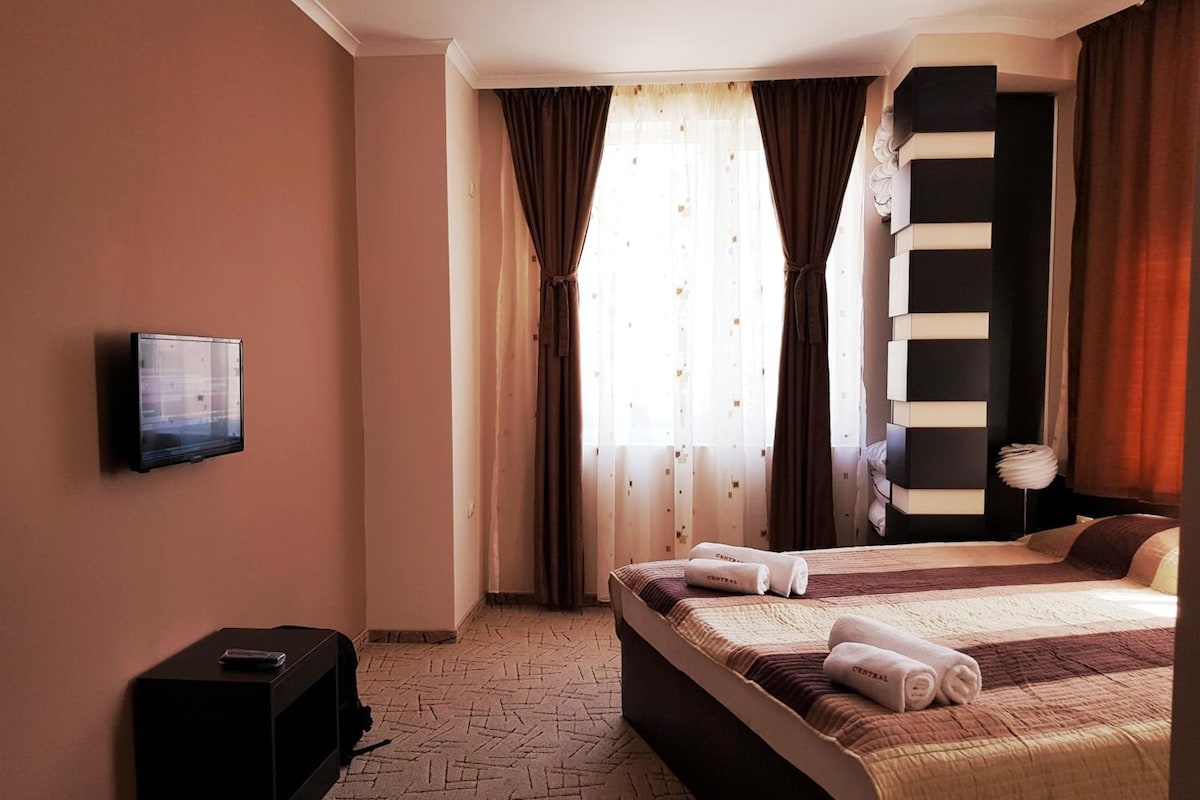 A hotel room with a bed, a television mounted on the wall, and a small table.