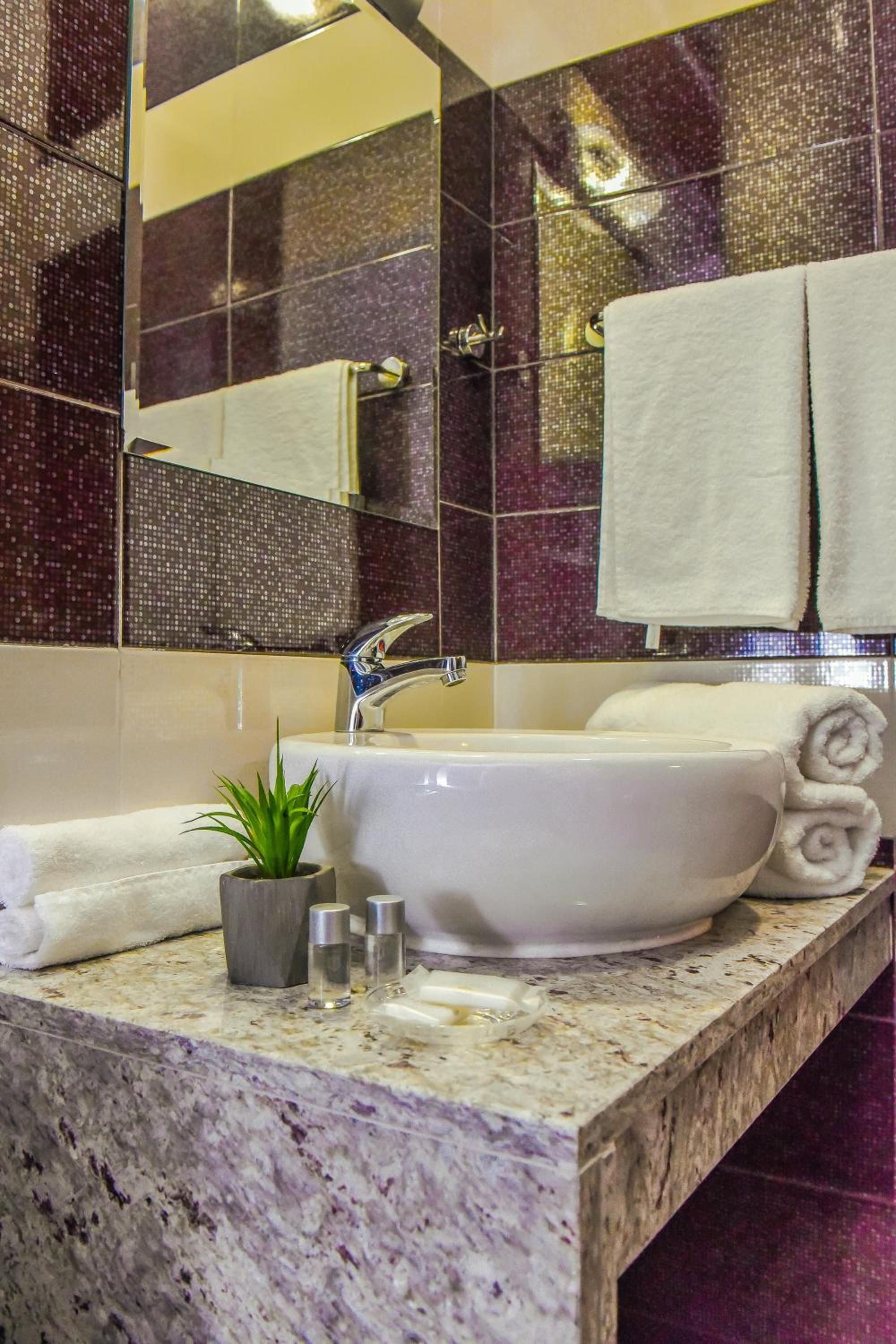 A bathroom with a white sink, a mirror, and a marble countertop.