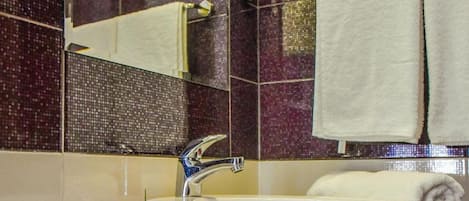 A bathroom with a white sink, a mirror, and a marble countertop.