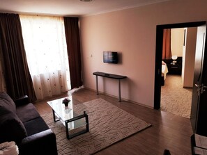 Una sala de estar con sofá, mesa de centro y televisión montada en la pared.