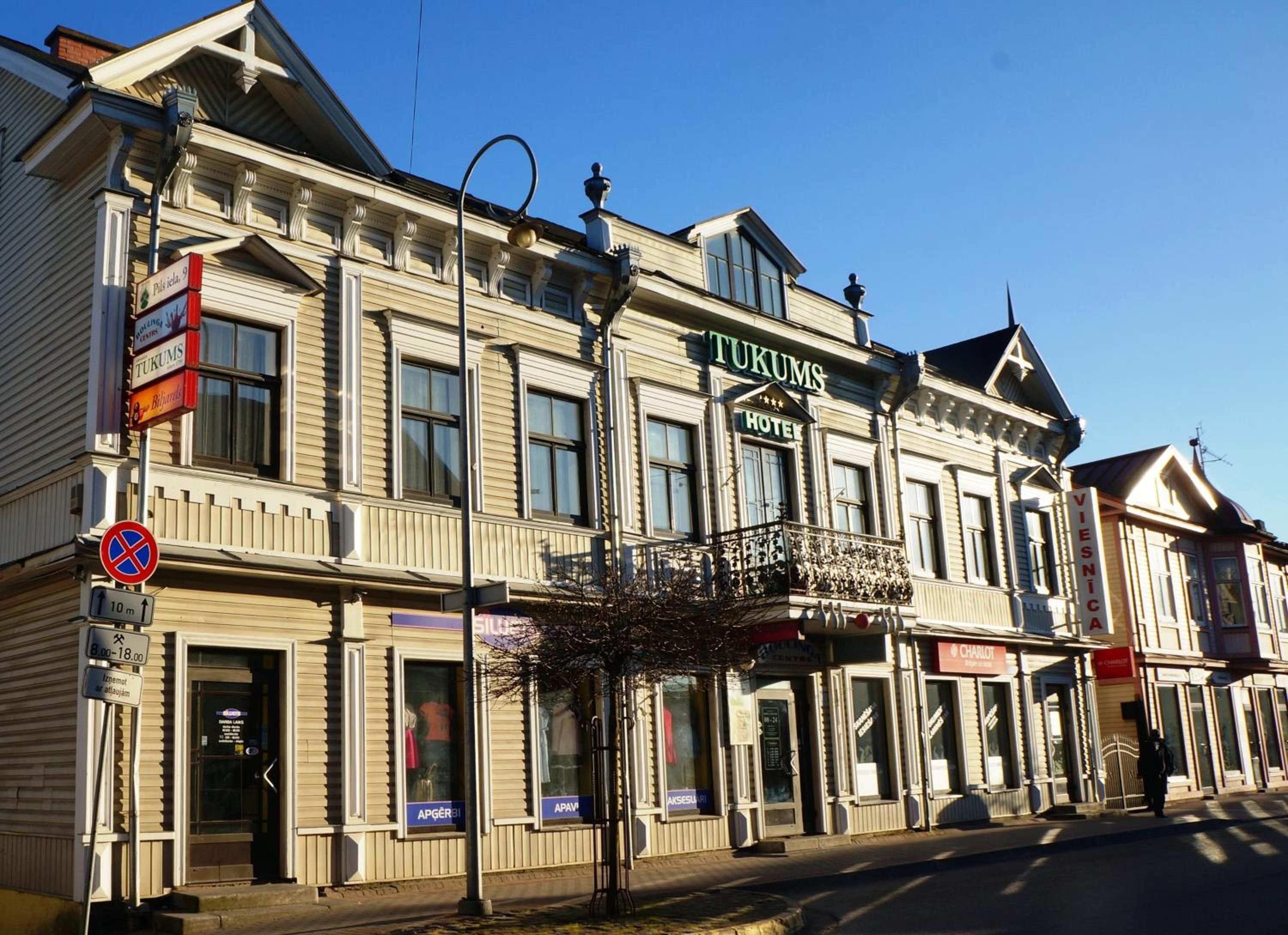 A historic building with a sign for 'TUKUMS HOTEL' and a 'VIESNICA' sign.