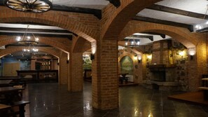 Un interior espacioso con arcos de ladrillo, chimenea de piedra y zona de bar.