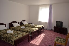 A hotel room with two single beds, a television, a chair, and a window with curtains.