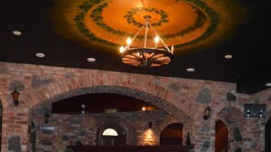 A room with a tiled floor, stone walls, a wooden bench, and a chandelier. - Hotel Tukums (Tukums)