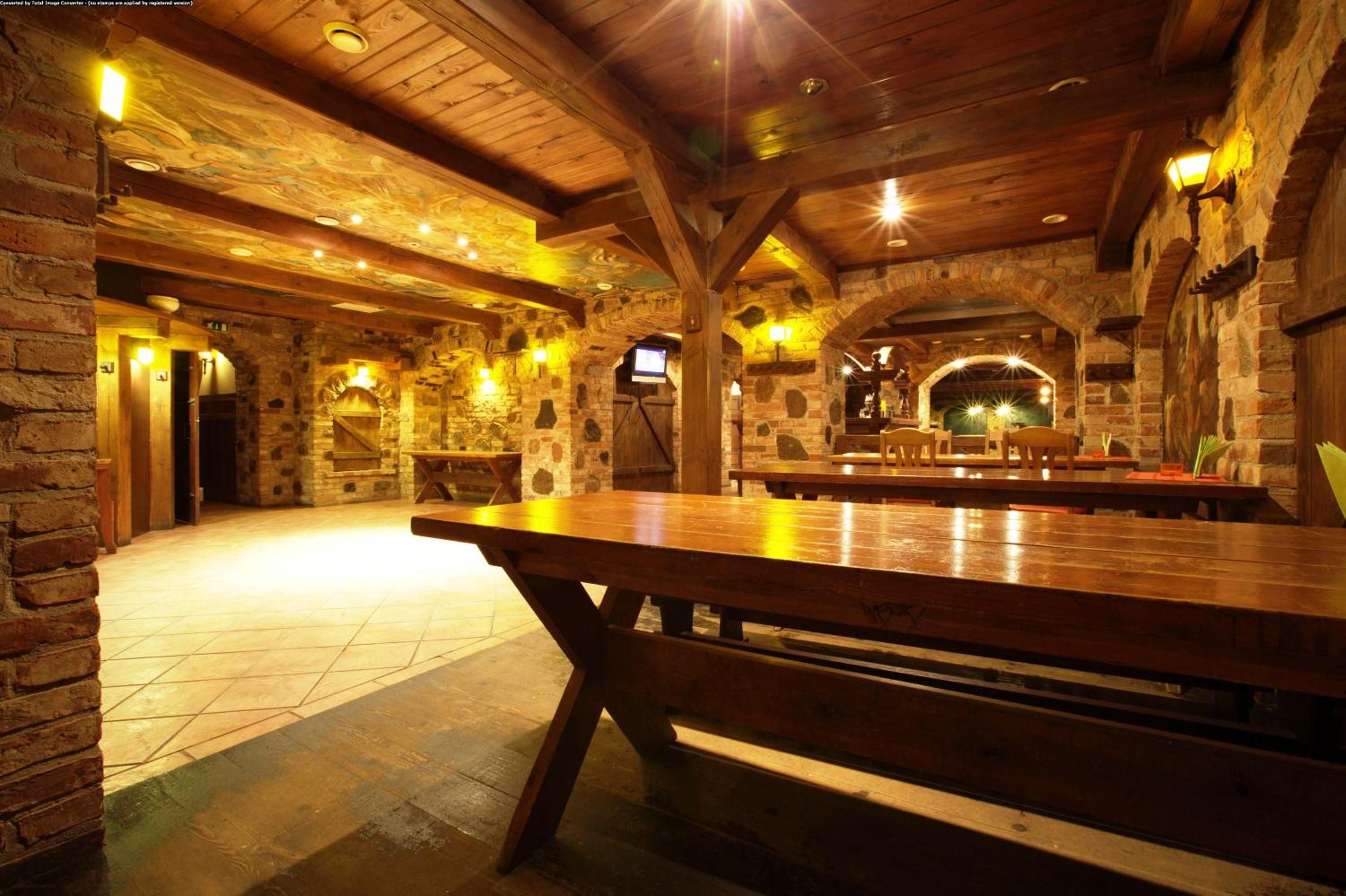 A rustic interior with stone walls, wooden beams, and a large wooden table.