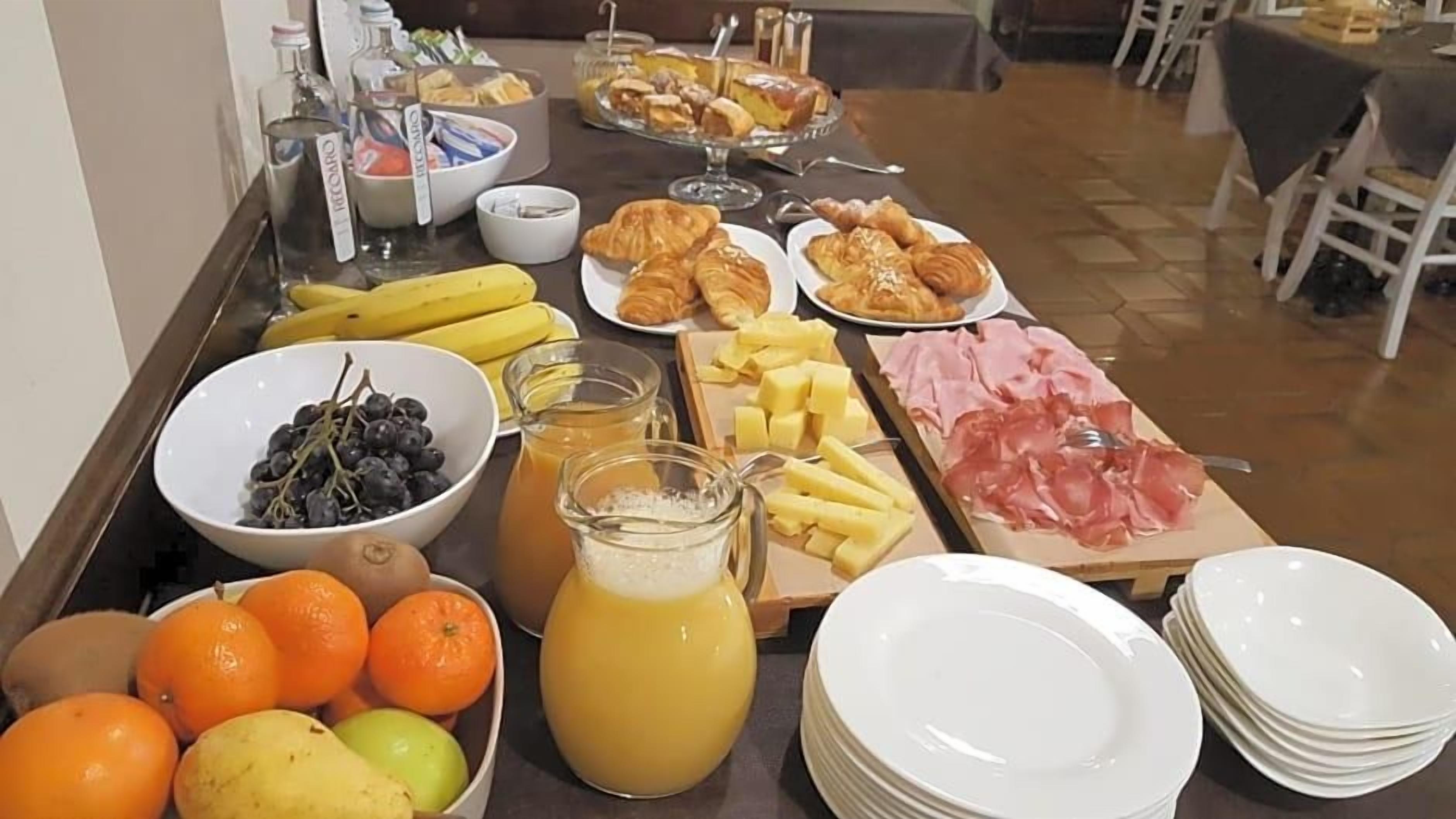 Une table de buffet proposant une variété d’aliments, notamment des fruits, des pâtisseries et du fromage.