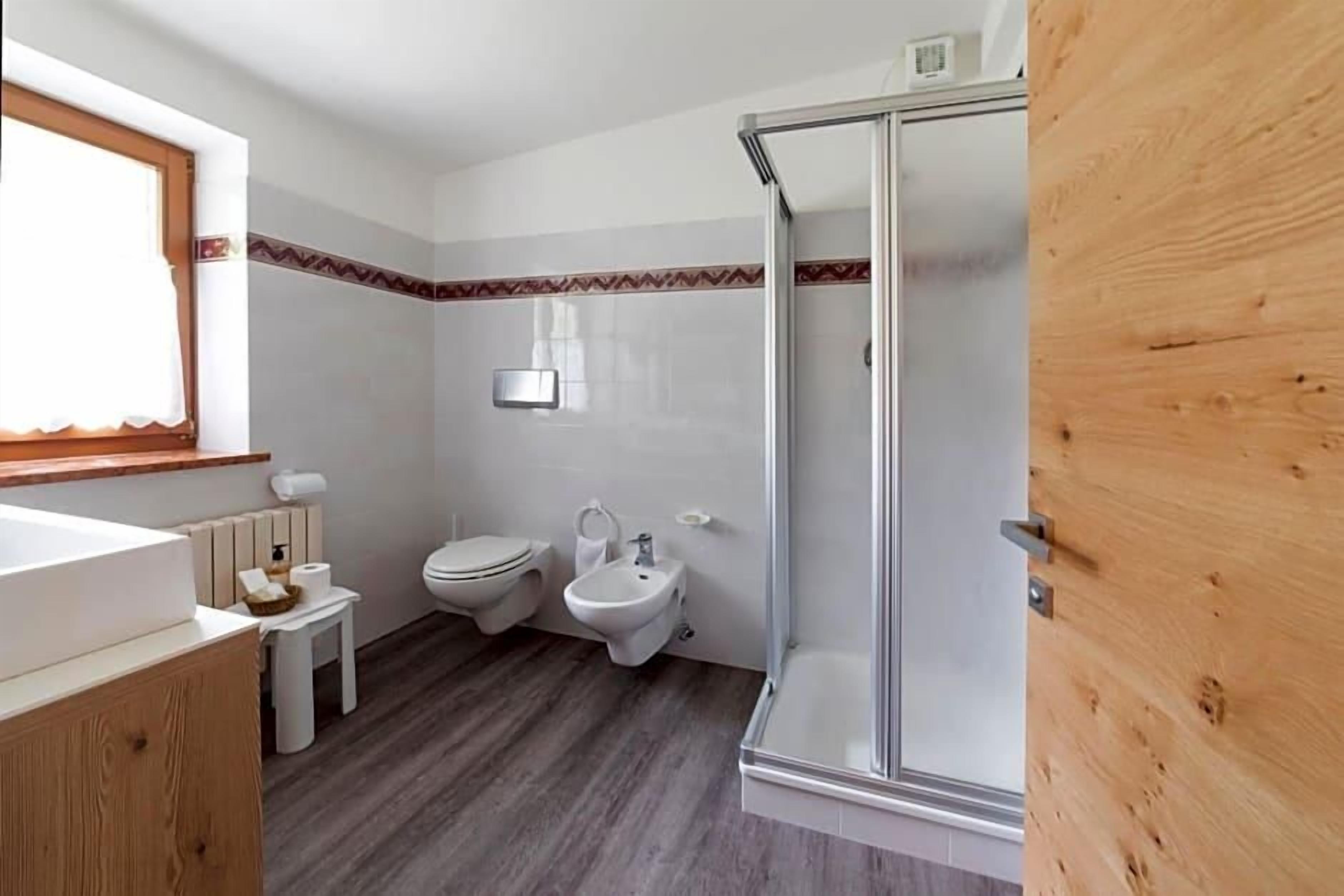 Ein Badezimmer mit Dusche, Toilette, Bidet und einem kleinen Tisch mit Pflegeprodukten.