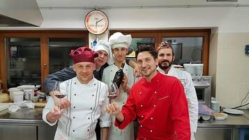 Eine Gruppe von Köchen in einer Küche mit Edelstahlflächen und einer Uhr an der Wand.