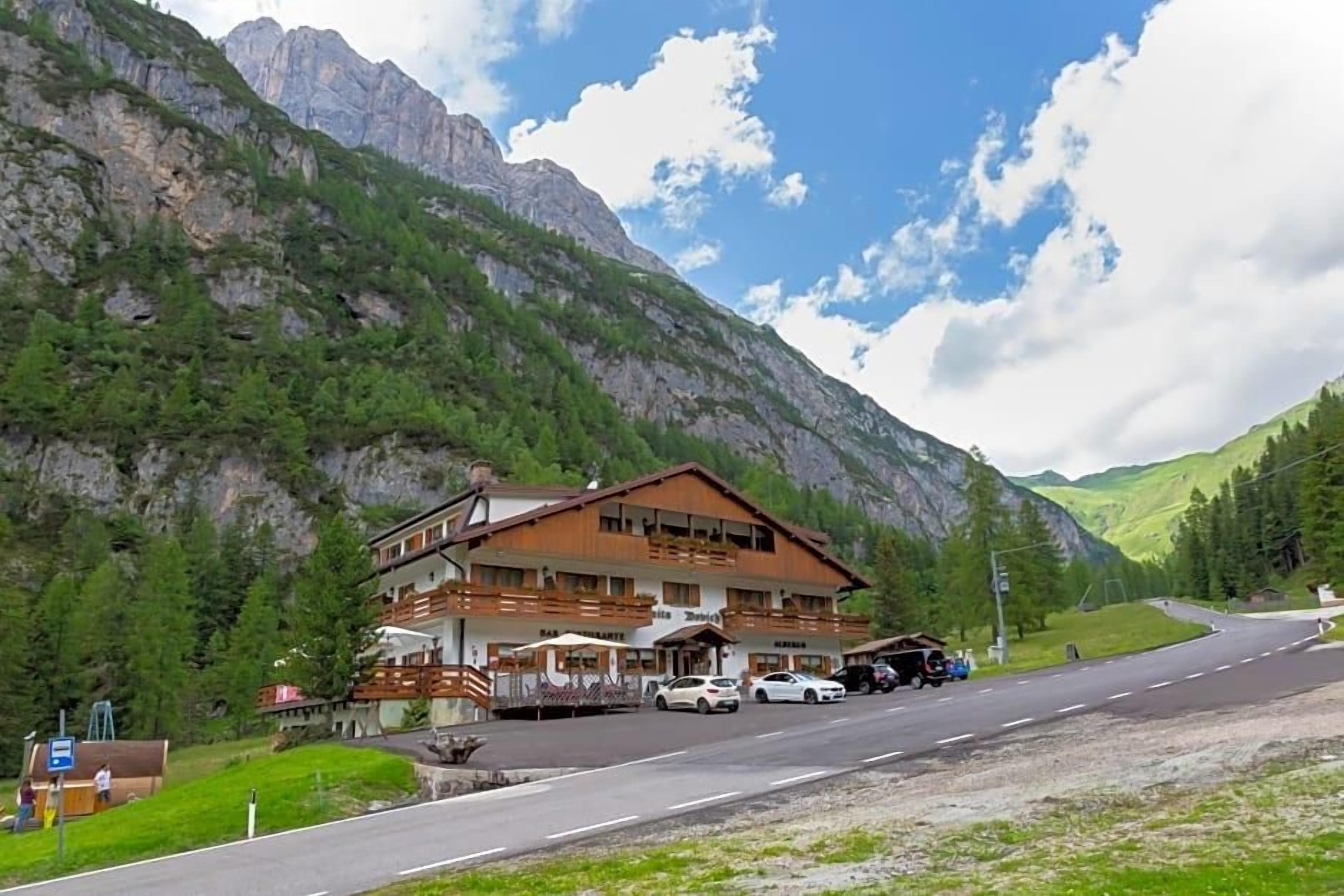 Eine Berghütte mit einem großen Gebäude, einem Parkplatz und einer Straße, die den Berg hinaufführt.