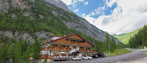 Un refugio de montaña con un edificio grande, un estacionamiento y una carretera que asciende por la montaña.