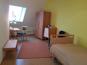 A room with a bed, a desk, a chair, a wardrobe, and a window.