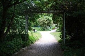 A paved pathway leading through a garden with a wooden pergola overhead. - Haus Aja Textor-goethe (Frankfurt)