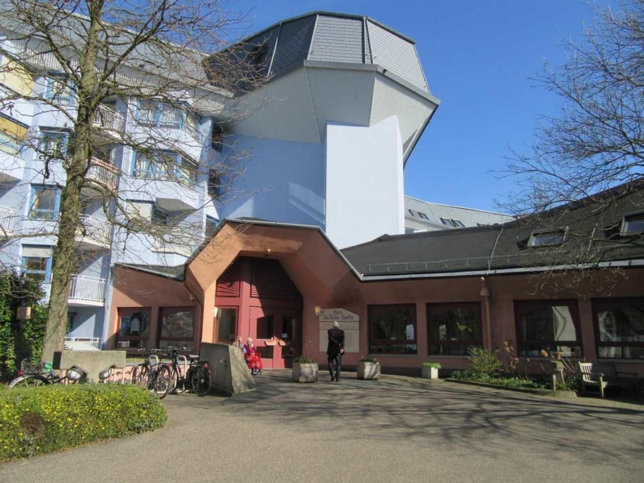 Um edifício com design arquitetônico único, destacando uma entrada vermelha marcante e uma grande área envidraçada.