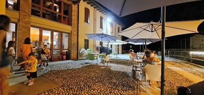 An outdoor dining area with tables and umbrellas, surrounded by a stone wall. - Ostello Molino Di Basso (Torre Pallavicina)