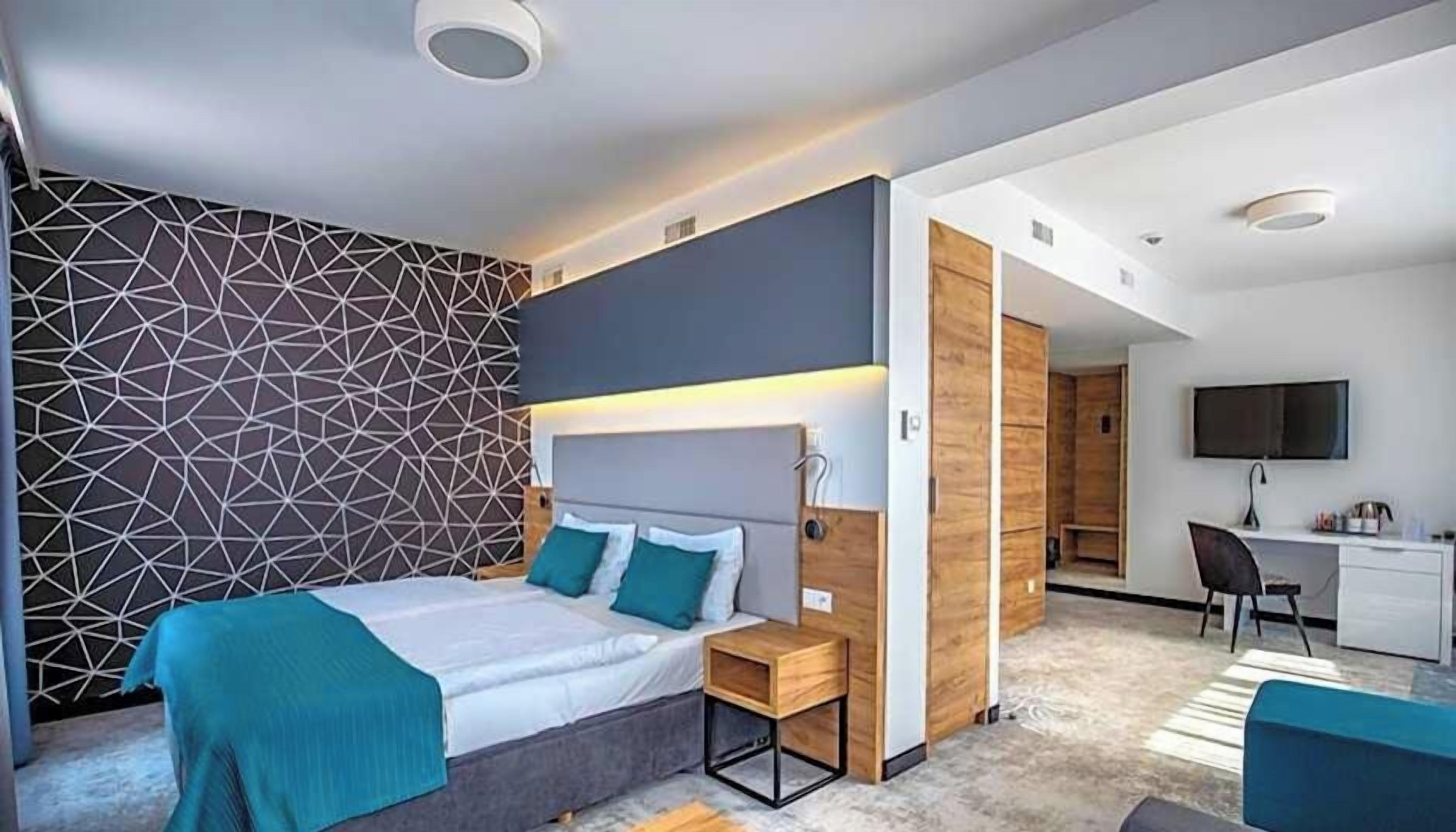 Un dormitorio moderno con cama, mesitas de noche, escritorio y televisor.