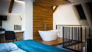 A modern bedroom with a large bed, a freestanding bathtub, and a desk area.