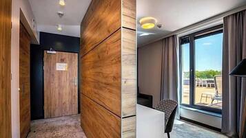 Habitación de hotel con un armario de madera, un escritorio y un ventanal con vistas al exterior.