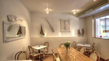 A dining area with a wooden table and chairs, a vase with flowers, and wall-mounted artwork.