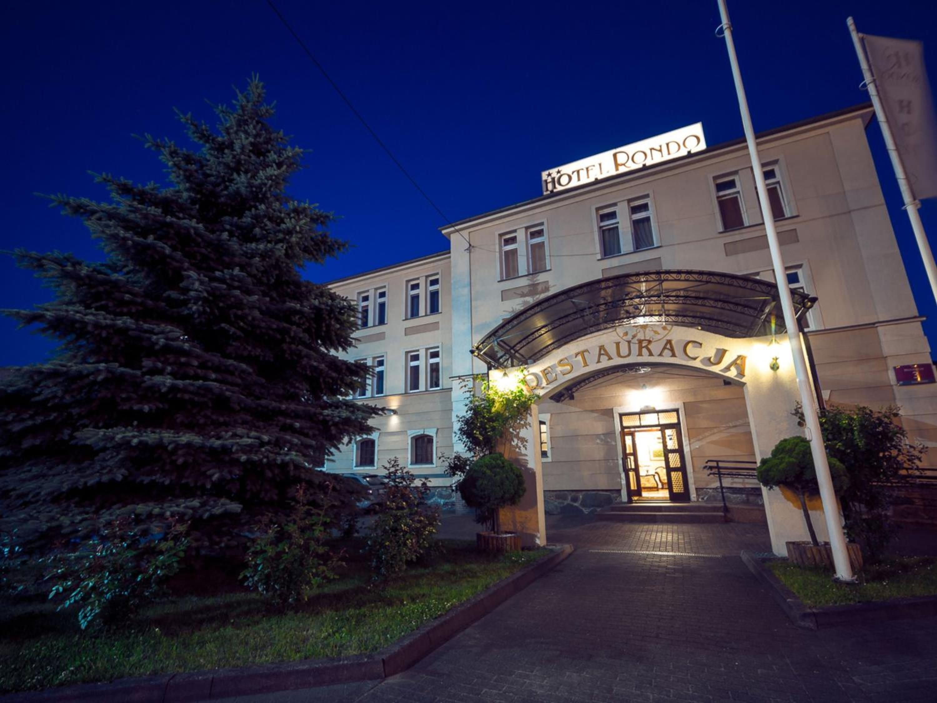 A hotel entrance with a sign reading 'HOTEL RONDO' and 'RESTAURACJA' indicating a restaurant.