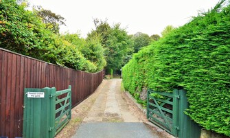 A narrow pathway leading to a gated area with a sign instructing to close the gate.