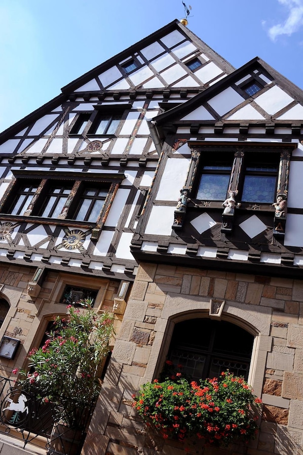 A half-timbered building with a stone base, multiple windows, and a small balcony with statues. - Weinkastell Zum Weissen Ross (Kallstadt)