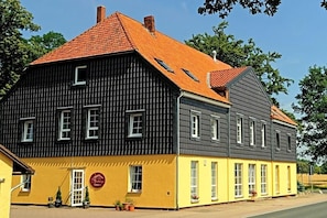 A two-story building with a yellow and black facade, multiple windows, and a red-tiled roof. - Landhaus Heidekrug (Diekholzen)