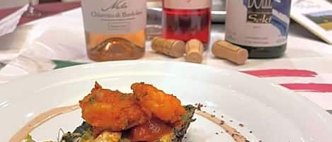 A plate of food with a bottle of wine and a bottle of olive oil on the table.