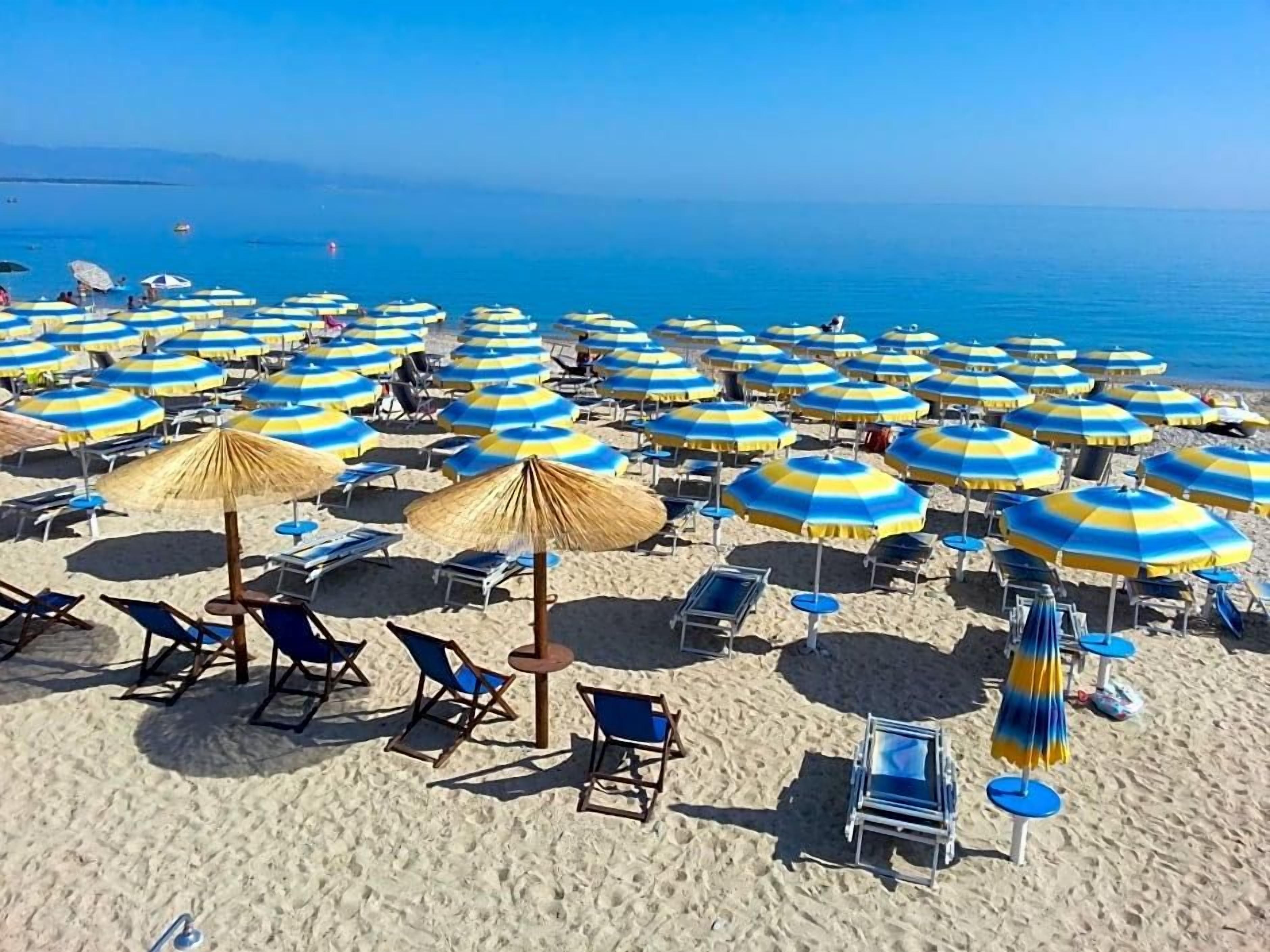 Una playa con numerosos sombrillas y sillas de playa.