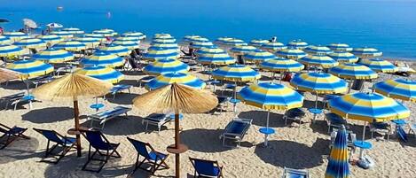 Una playa con numerosos sombrillas y sillas de playa.