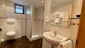 Een badkamer met toilet, wastafel, douche en een handdoekrek.