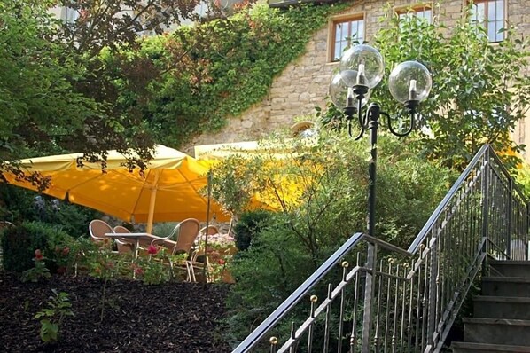 A staircase with a metal railing, a yellow umbrella, and outdoor furniture. - Schlosshotel Ingelfingen (Ingelfingen)