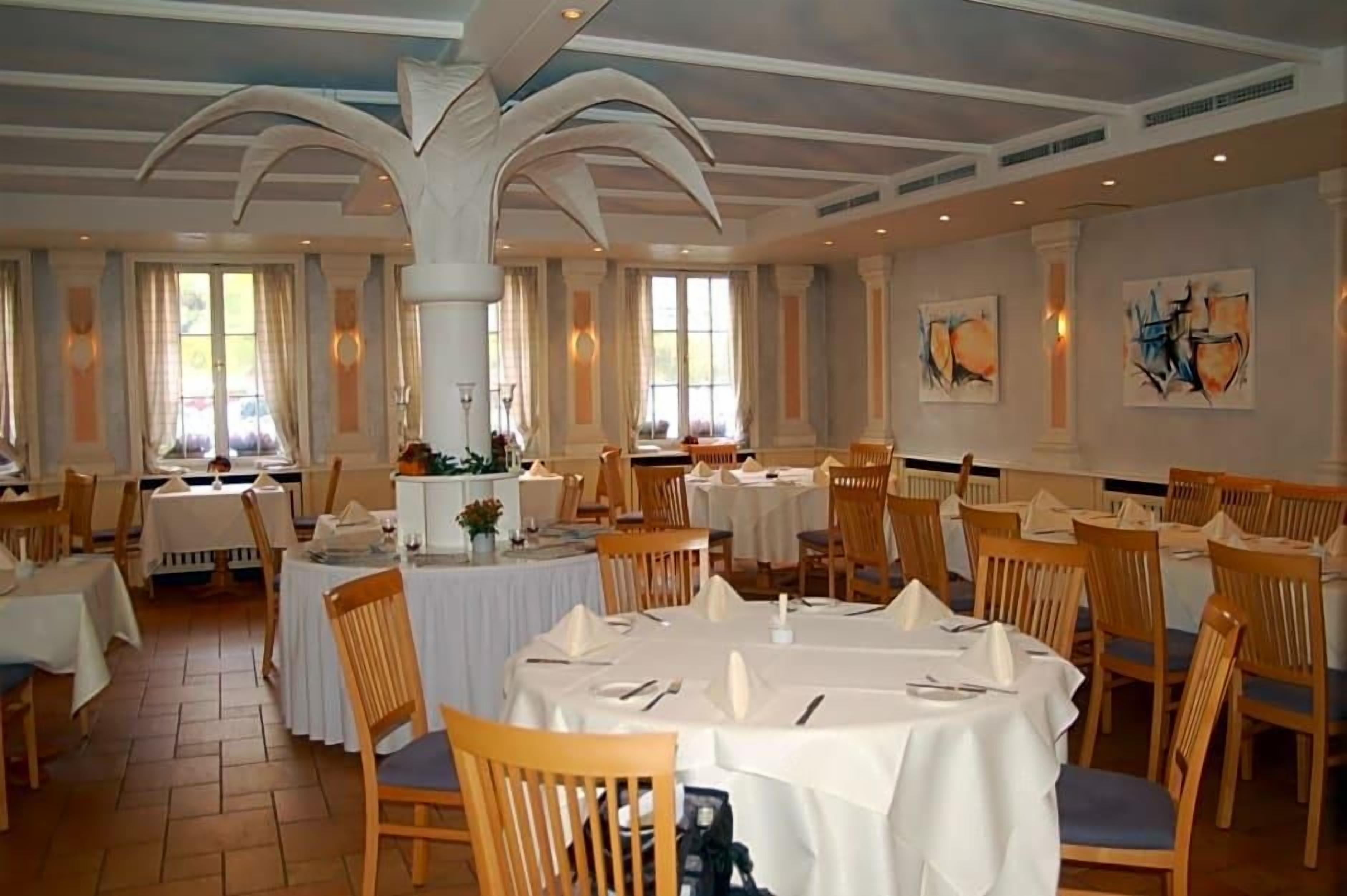 A dining area with round tables, chairs, and a high ceiling with decorative moldings.