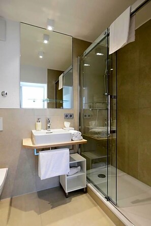 A modern bathroom with a glass shower enclosure, a white sink, and a mirror above it. - Schlosshotel Ingelfingen (Ingelfingen)