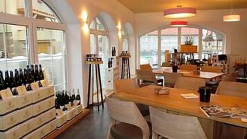 A restaurant with a long wooden table, chairs, and a wine display.