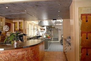 A hotel kitchen with stainless steel appliances, a bar area, and a counter with a plant. - Schlosshotel Ingelfingen (Ingelfingen)