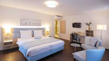 A hotel room with a bed, a desk, a chair, and a television.