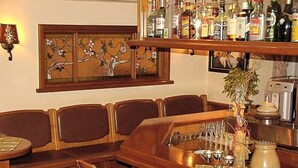 A bar area with wooden furniture, a variety of liquor bottles, and a decorative plant. - Ackfeld Hotel Restaurant (Bueren)