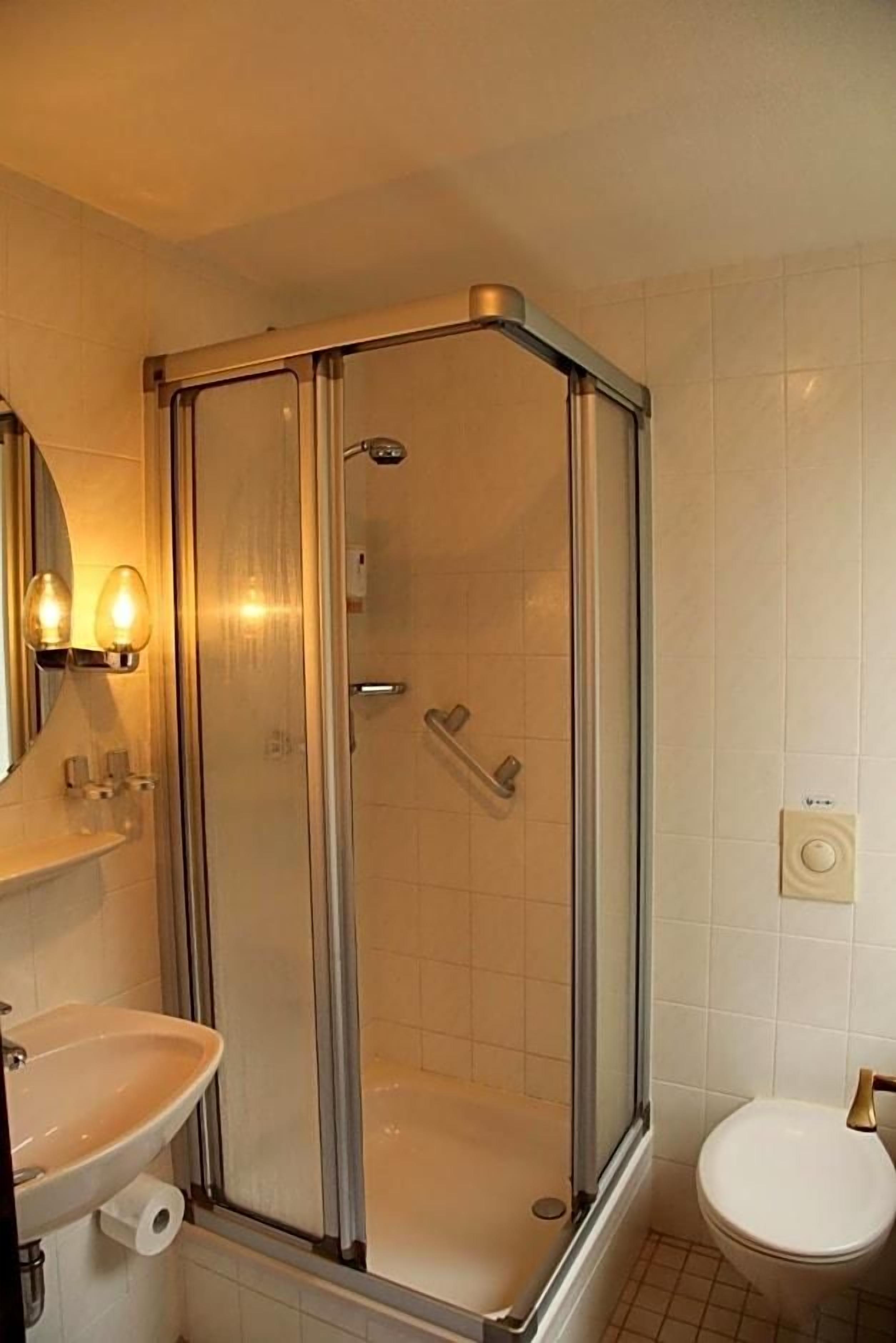 A bathroom with a glass-enclosed shower, a sink, and a toilet.