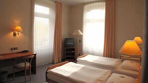 A hotel room with two beds, a desk, a television, and lamps. - Ackfeld Hotel Restaurant (Bueren)