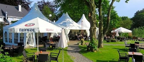 Un espace jardin aménagé avec des sièges extérieurs, des tentes blanches et un chemin de gravier.