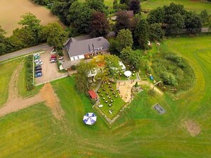 An aerial view of a property with a large house, a parking area, and a well-maintained lawn. - Bredeneeker Gasthaus (Rastorf)