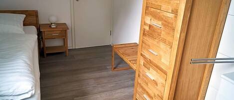 Un dormitorio con una cama, un armario de madera, una mesita de noche y un buró.