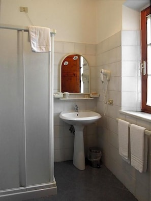 A bathroom with a shower, sink, mirror, and towel rack.