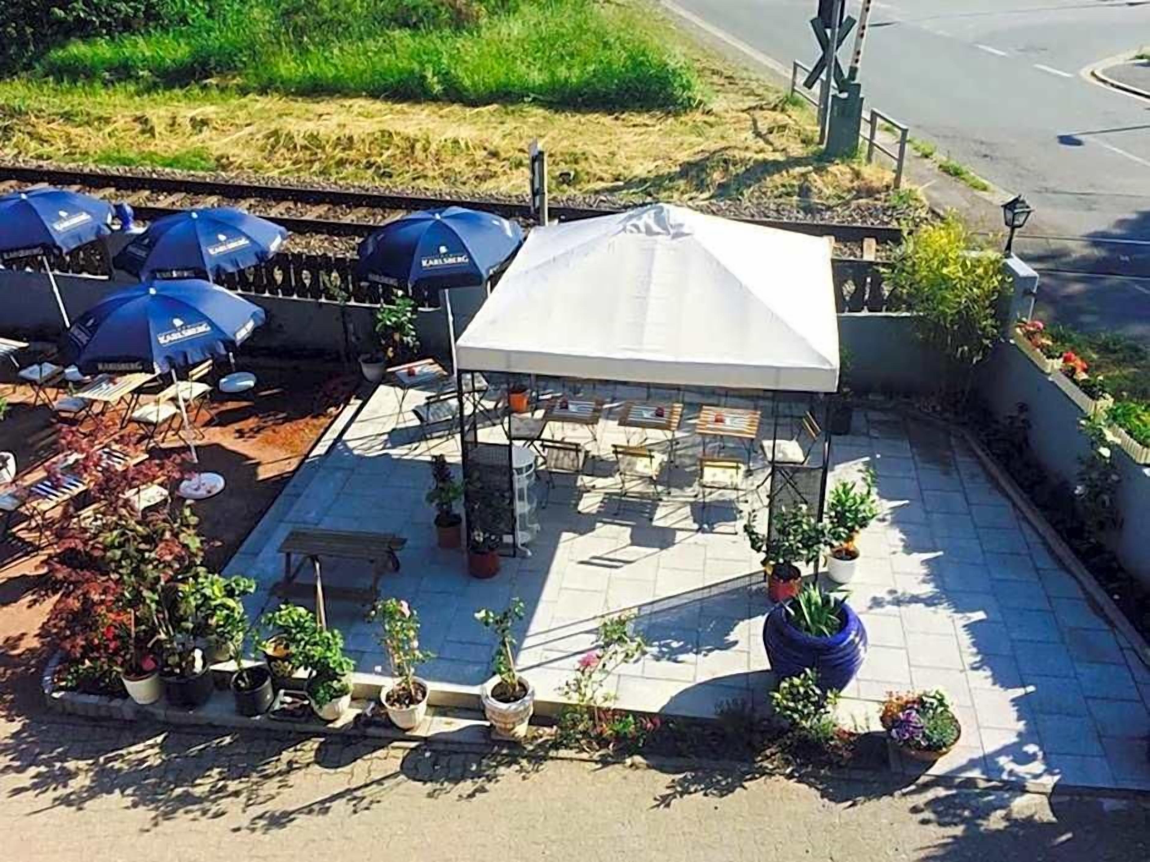 Een terras met parasols, tafels en plantenpotten.