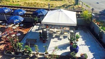 Een terras met parasols, tafels en plantenpotten.