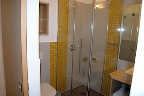 A bathroom with a glass-enclosed shower, a toilet, and a sink.