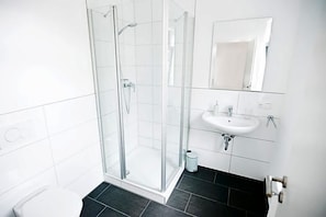 A modern bathroom with a glass-enclosed shower, a white sink, and a mirror. - Alte Heimat (Berge)