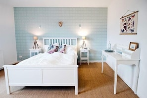 A bedroom with a white bed, two bedside tables with lamps, a white desk, and a wall-mounted shelf. - Alte Heimat (Berge)